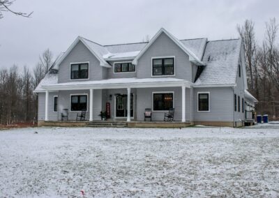 The Owasco custom home. 2 stories, gray exterior with 4 white beams around front porch